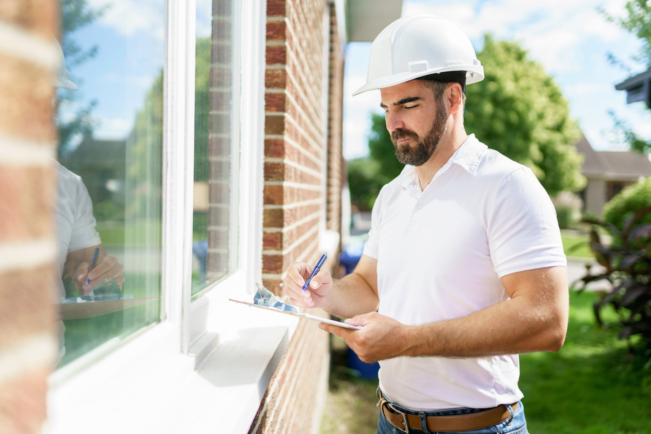 man with a white hard hat holding a clipboard, inspect house